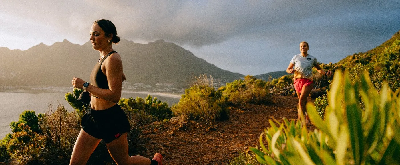 2 people running at a cliff near an ocean